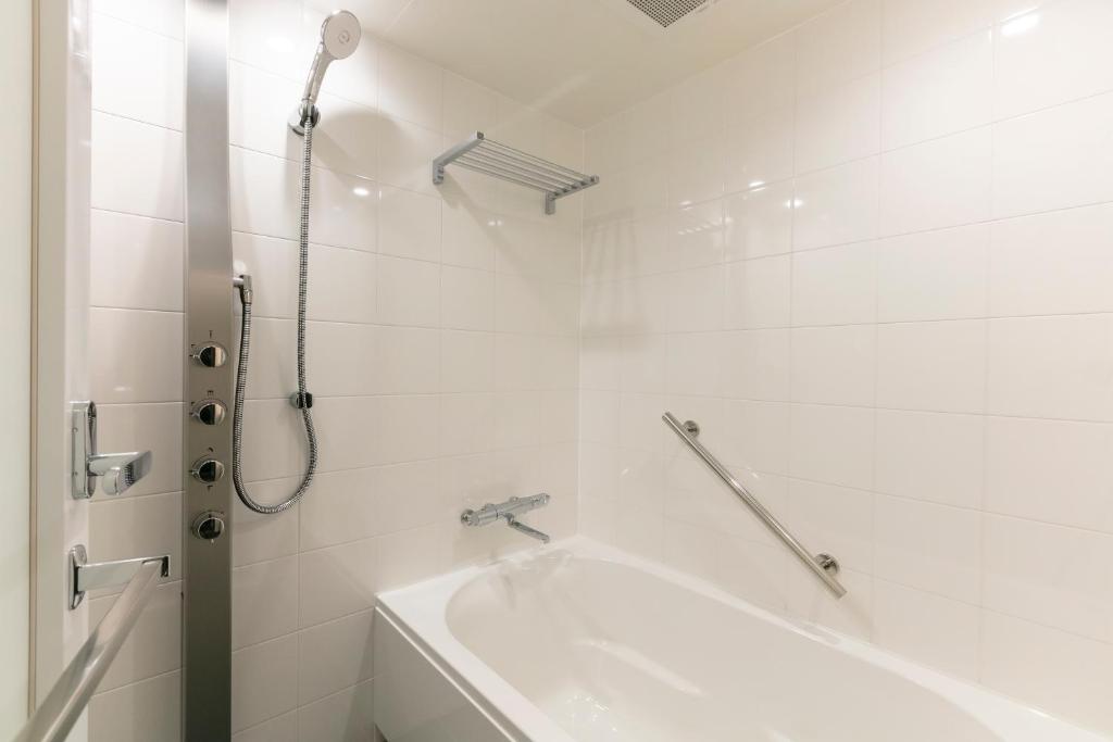 a white bathroom with a shower and a bath tub at Hotel Forza Osaka Namba in Osaka