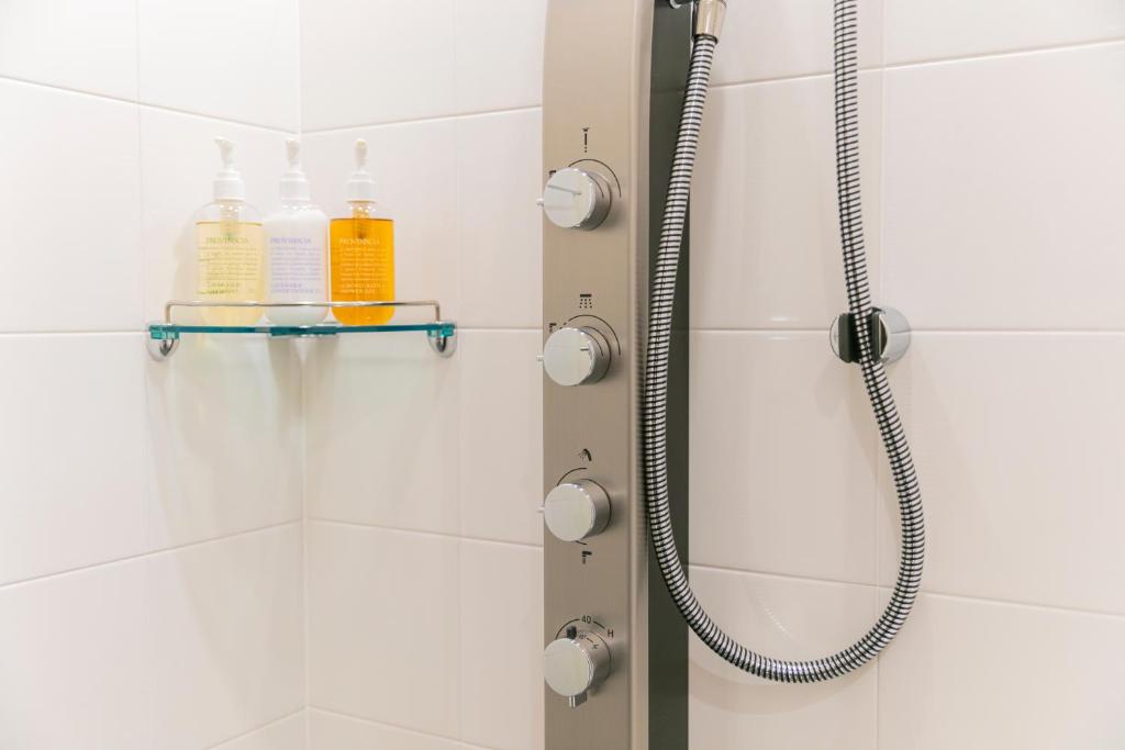 a shower in a bathroom with white tiles at Hotel Forza Osaka Namba in Osaka