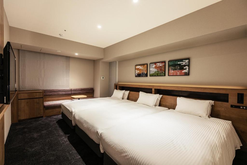 a hotel room with two beds and a flat screen tv at Hotel Forza Osaka Namba in Osaka