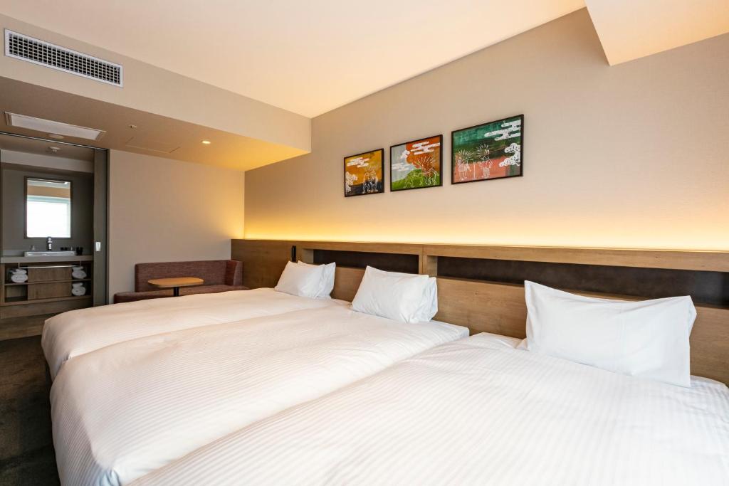 two beds in a hotel room with white sheets at Hotel Forza Osaka Namba in Osaka