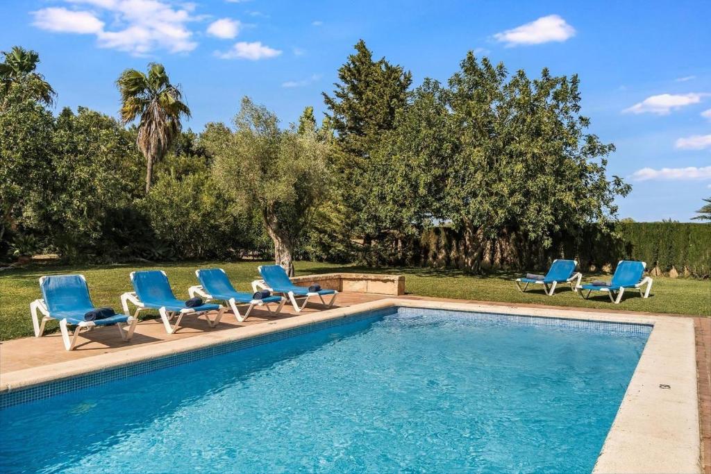 a swimming pool with blue chairs and a swimming poolvisorvisor at Finca Can Moleta in Cala Mendia