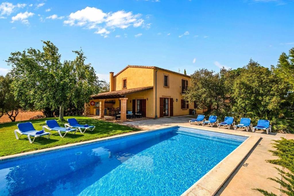 a villa with a swimming pool and blue chairs at Finca Vista Alegre in Cala Mendia