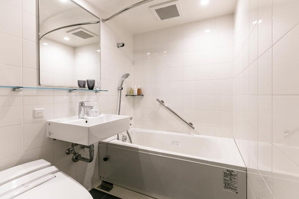 a white bathroom with a sink and a tub at Hotel Forza Osaka Namba in Osaka