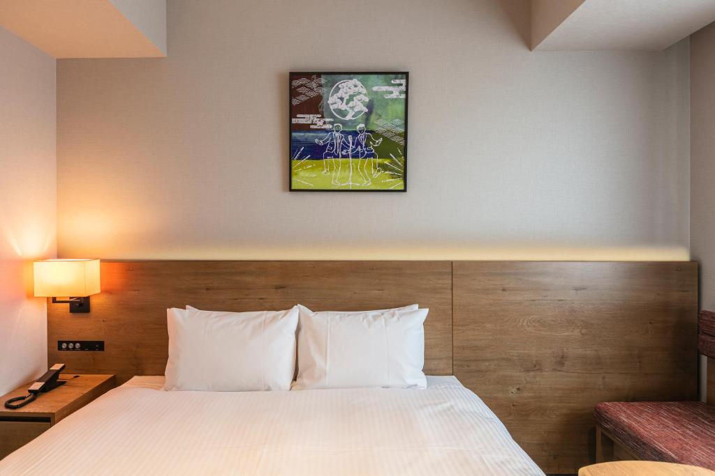 a hotel room with a bed and a picture on the wall at Hotel Forza Osaka Namba in Osaka