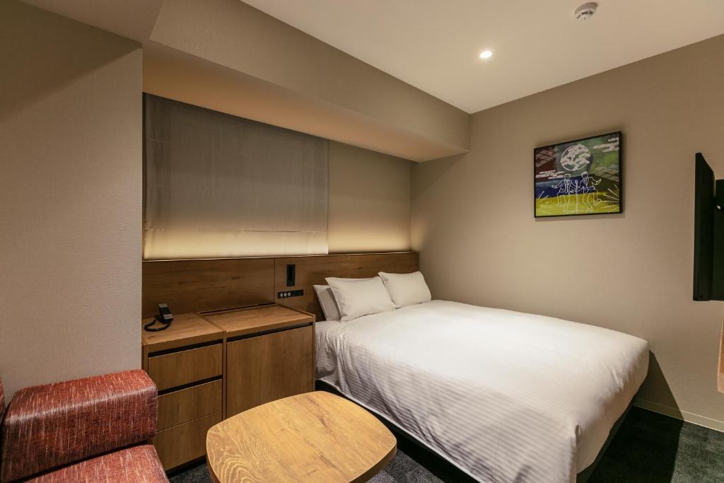 a small bedroom with a bed and a chair at Hotel Forza Osaka Namba in Osaka
