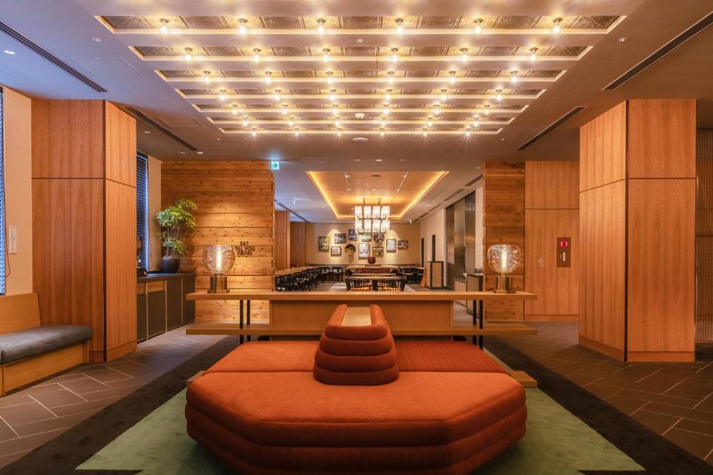 a living room with an orange ottoman and a kitchen at Hotel Forza Osaka Namba in Osaka