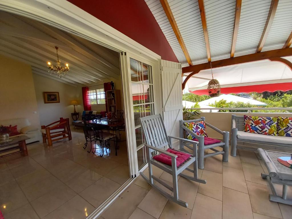 una veranda con sedie a dondolo e una sala da pranzo di Les Gites Capra - Tiatanne a Saint-François