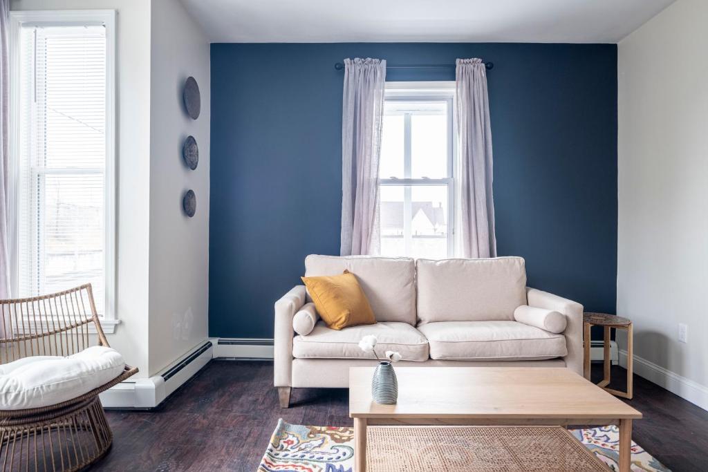Providence Modern, Comfy 3BR Apartment في بروفيدينس: غرفة معيشة مع أريكة بيضاء وجدار أزرق