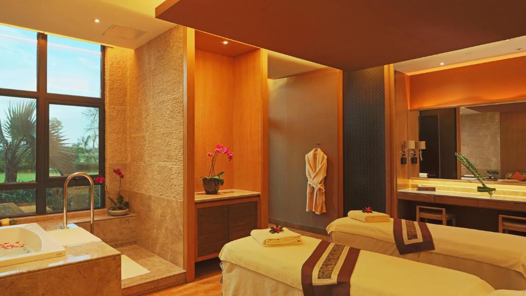 a bathroom with two beds and a sink and a tub at Grand Hotel Haikou - Managed by Accor in Haikou
