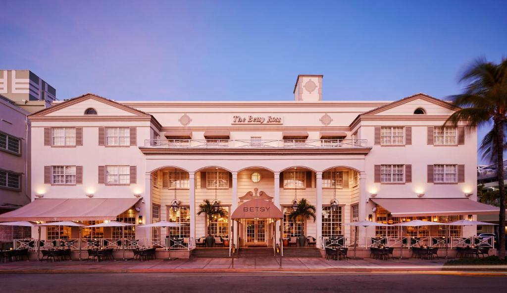 - un grand bâtiment blanc avec des tables devant dans l'établissement The Betsy Hotel, South Beach, à Miami Beach