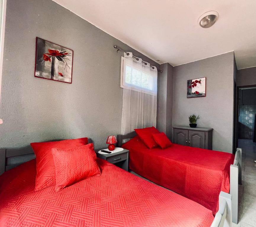 2 camas en un dormitorio con sábanas rojas en L organdi, en Cornebarrieu