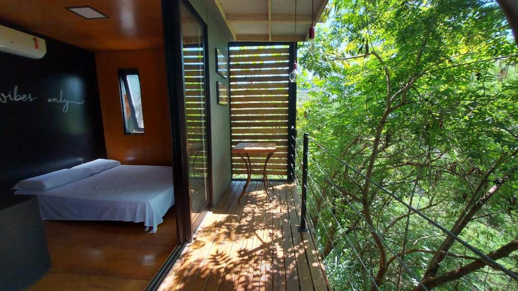 um quarto com uma cama e uma varanda com árvores em Casa da Árvore espaço Vila da Serra em Nova Lima