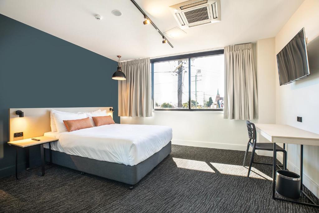 a hotel room with a bed and a desk and a window at Nightcap at Chardons Corner Hotel in Brisbane