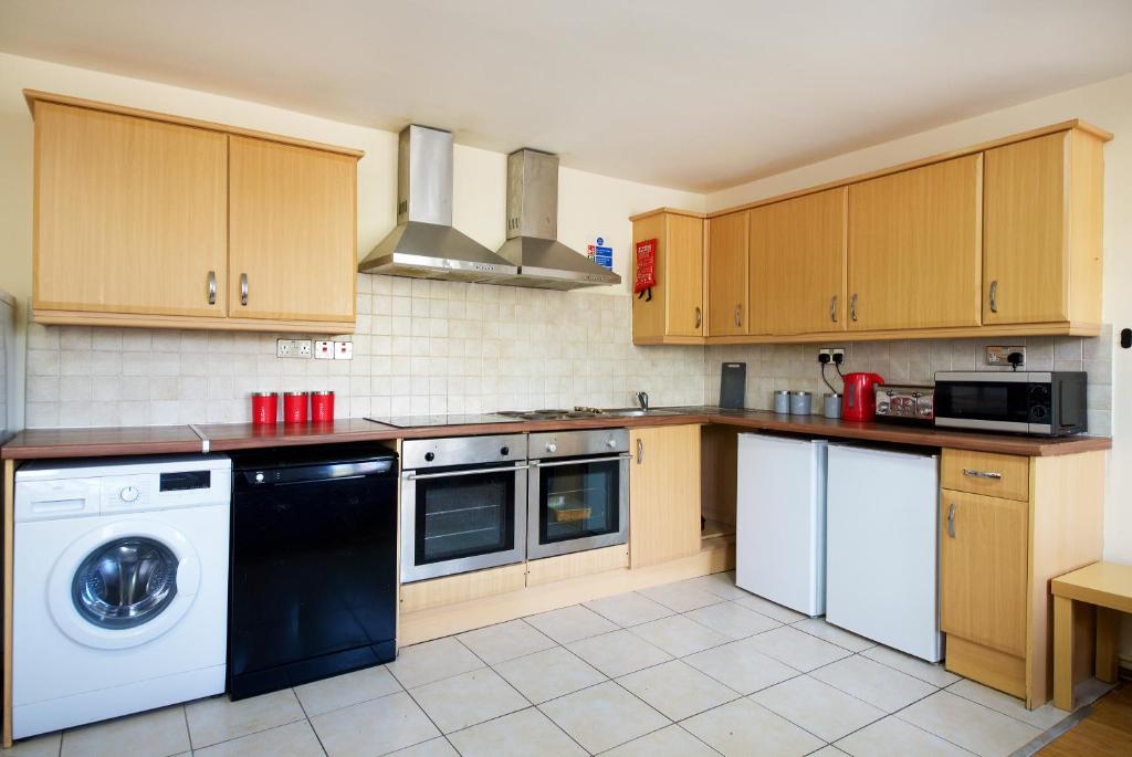 a kitchen with wooden cabinets and a washer and dryer at Liverpool City Centre Private Rooms including smart TVs - with Shared Bathroom in Liverpool