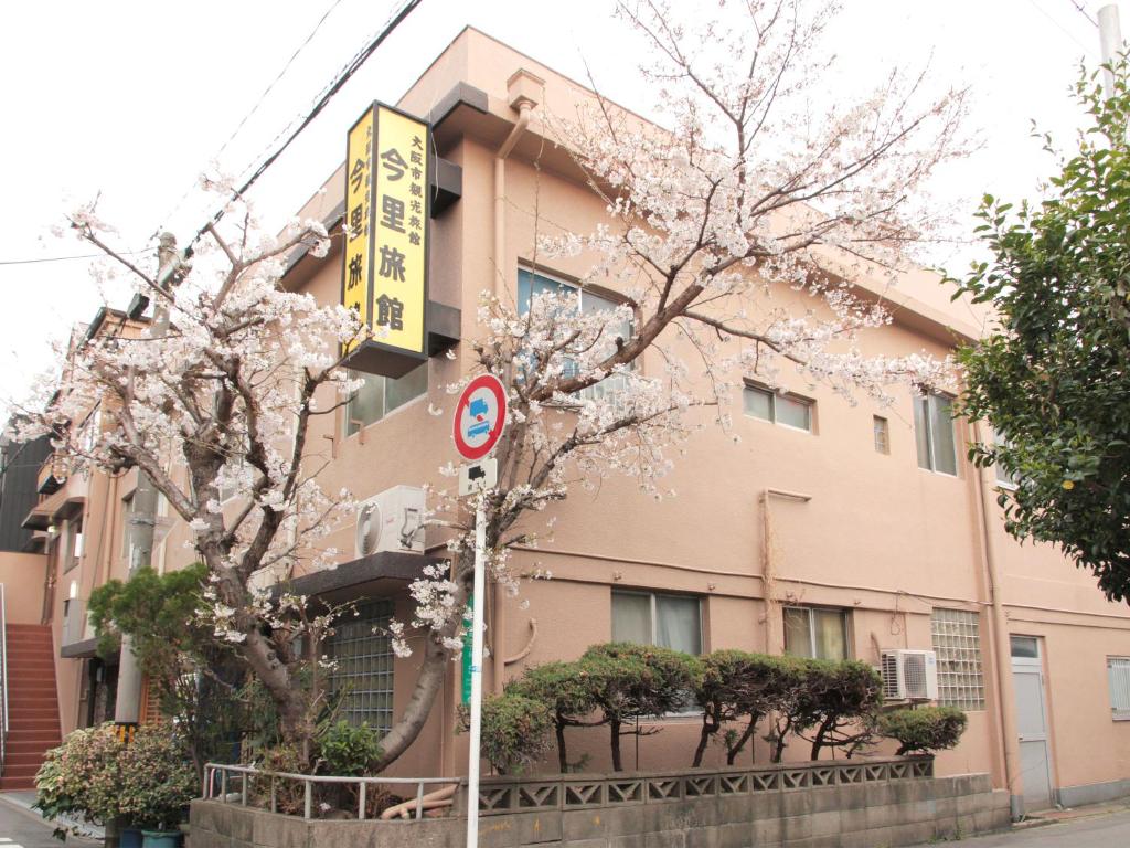 un edificio con un árbol florido delante de él en Imazato Ryokan, en Osaka