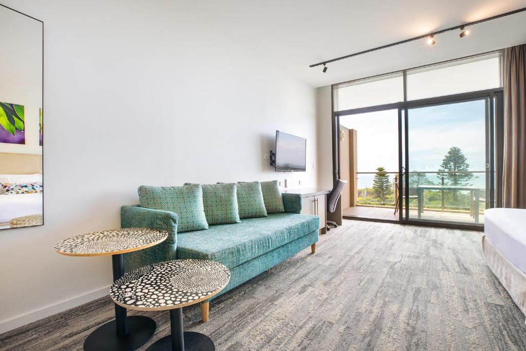 a living room with a couch and a large window at Narrabeen Sands Hotel by Nightcap Plus in Narrabeen