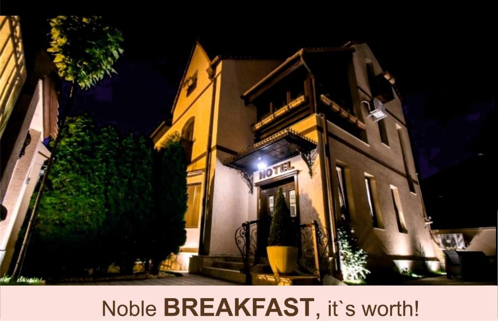 um edifício com uma placa na frente à noite em Noblesse Boutique Resort em Sibiu