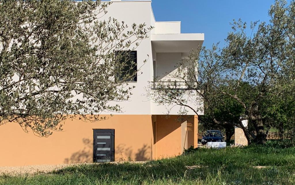 een wit en oranje huis met een auto in een veld bij MiaBella Resort in Drage