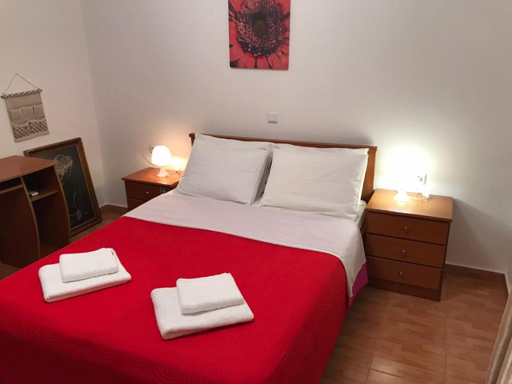 a bedroom with a red bed with two towels on it at ziogas apartments in Plataria