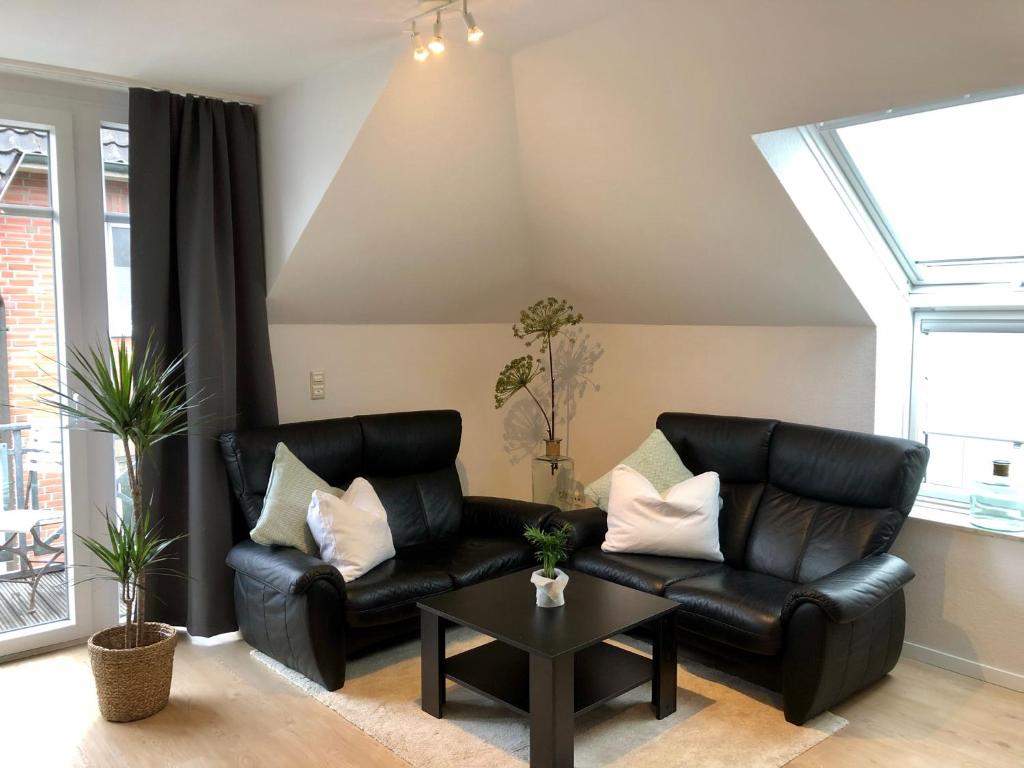 a living room with a black leather couch and a table at Apartment in Uni- und Citynähe in Oldenburg