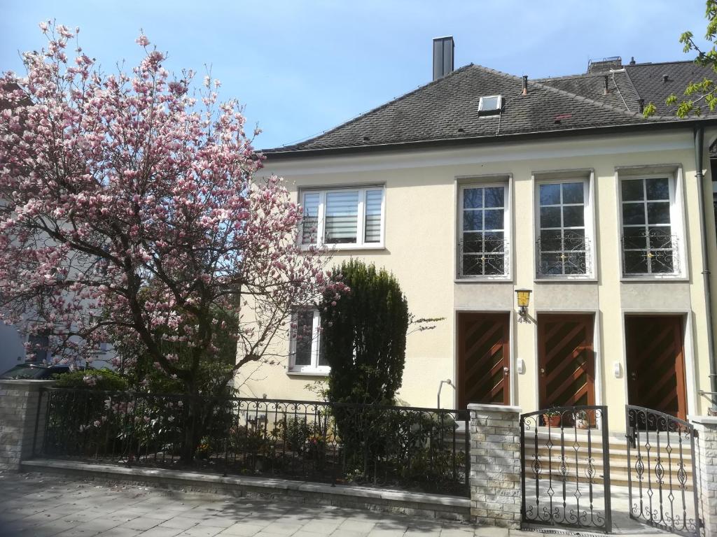 a white house with a fence and a tree at Ferienwohnung im Hain in Bamberg