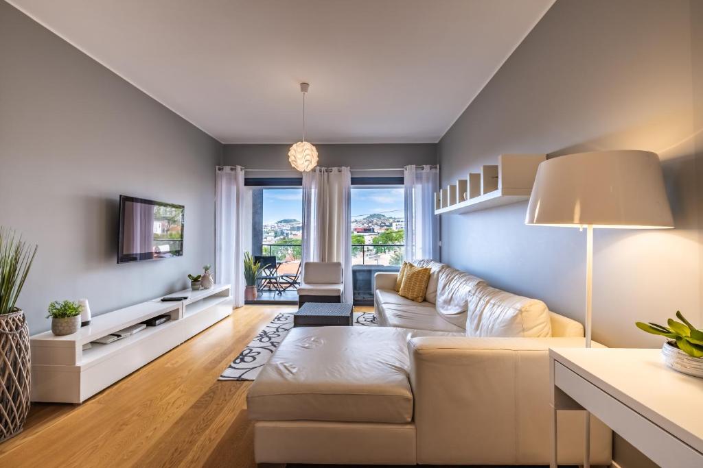 een woonkamer met een witte bank en een tv bij Green Apartment in Funchal