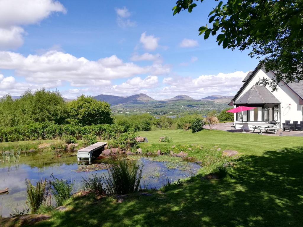 ein Gebäude mit einer Bank neben einem Teich in der Unterkunft Misty Bay - Kenmare in Kenmare