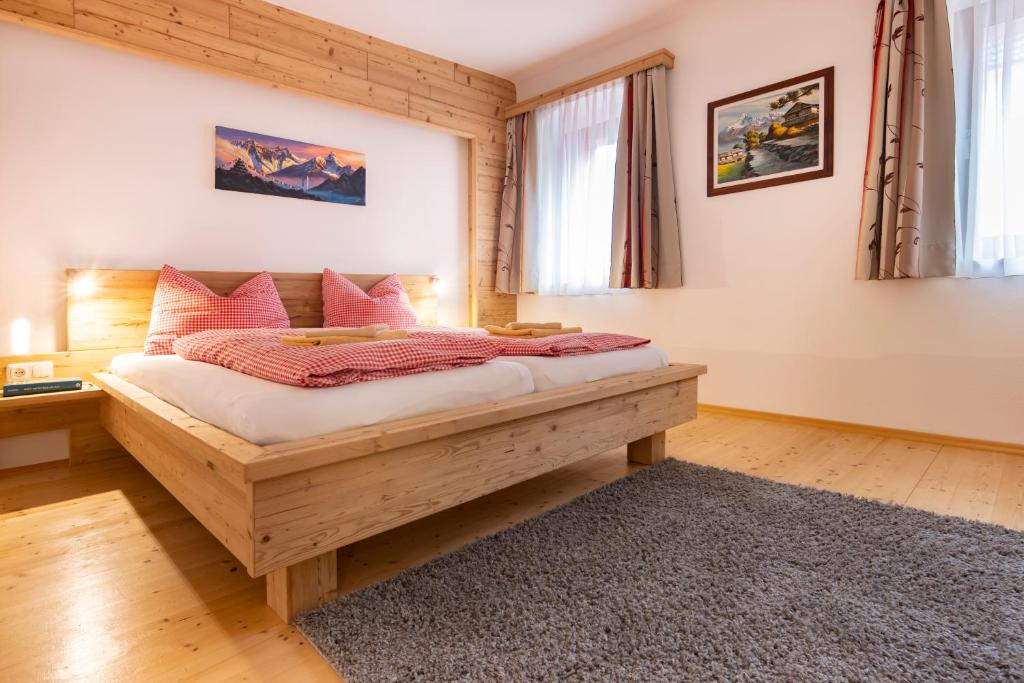 a bedroom with a large wooden bed with pink pillows at Camping & Pension Au an der Donau in Au an der Donau