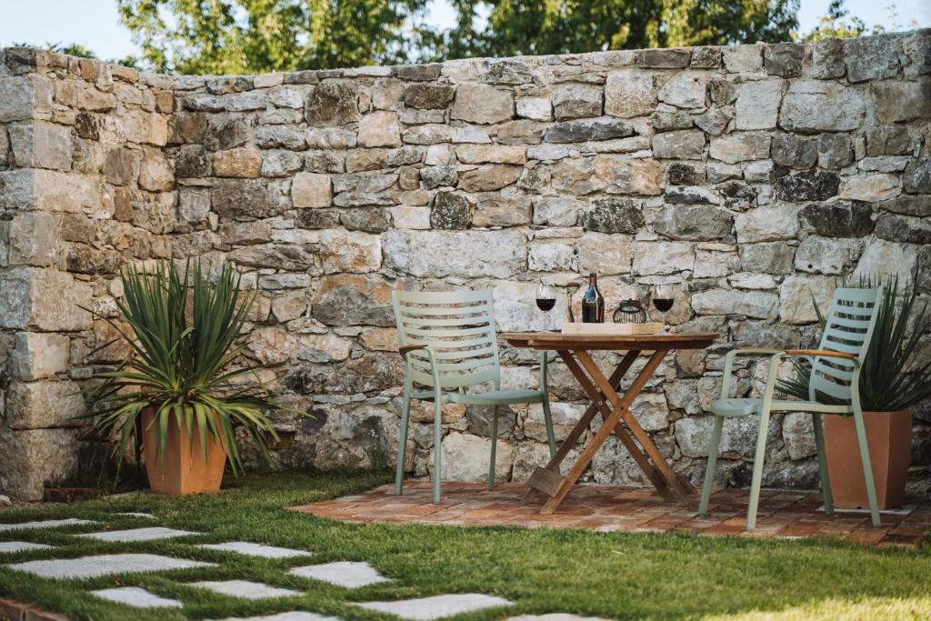 a table and chairs next to a stone wall at Apartma Ob stari murvi, Sežana in Sežana