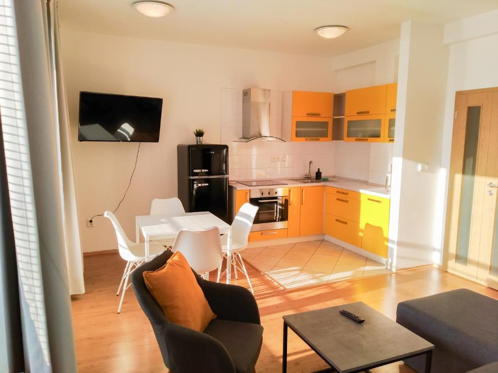 a living room with a table and a kitchen with yellow cabinets at Yellow Apartment in Ostrava