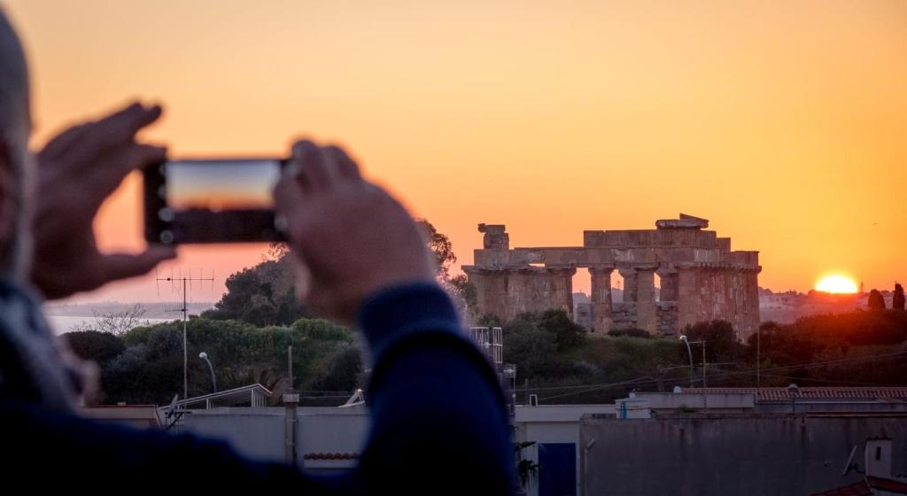 een persoon die een foto neemt van de acropolis bij zonsondergang bij Il terrazzo dei templi in Marinella di Selinunte