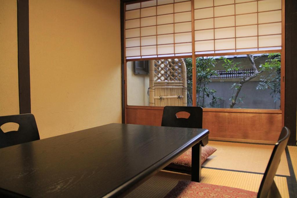 a dining room with a table and chairs and a window at Demizu Machiya Machiya Inn in Kyoto