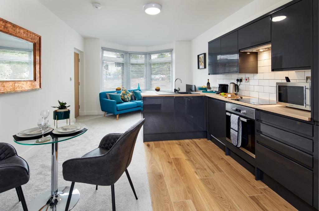a kitchen with black cabinets and a blue couch at Coppergate Mews Apartment 2 in Doncaster