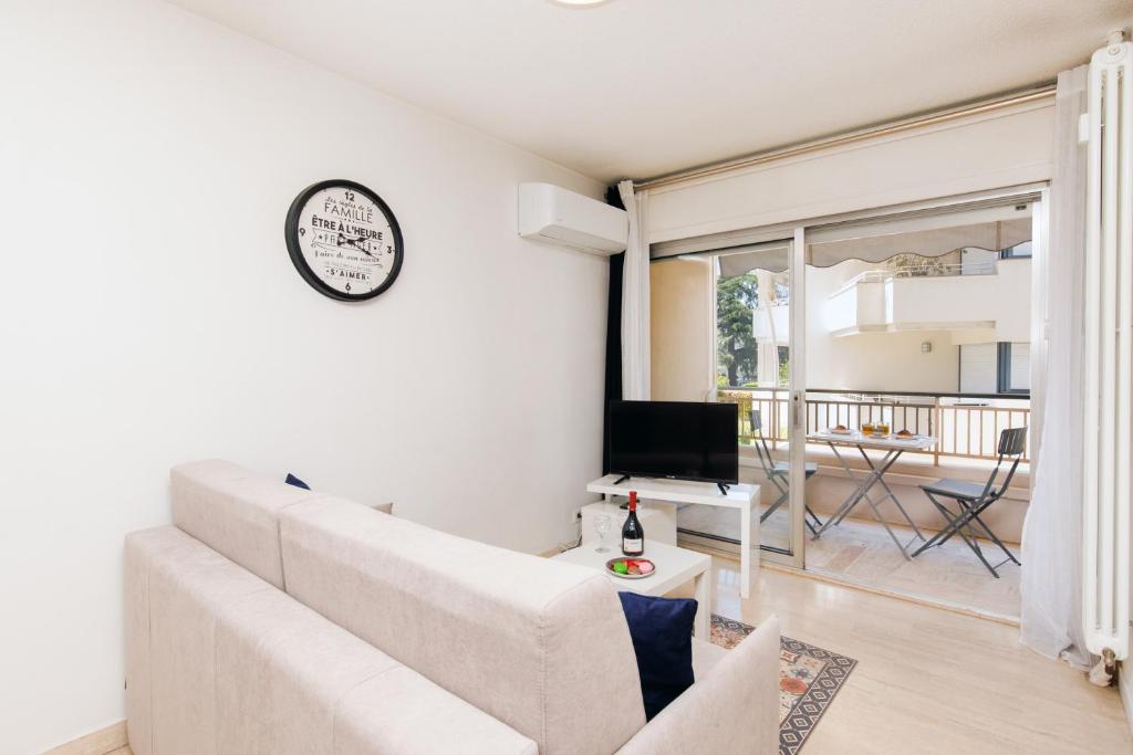 sala de estar con sofá y reloj en la pared en Antares S YourHostHelper, en Cannes