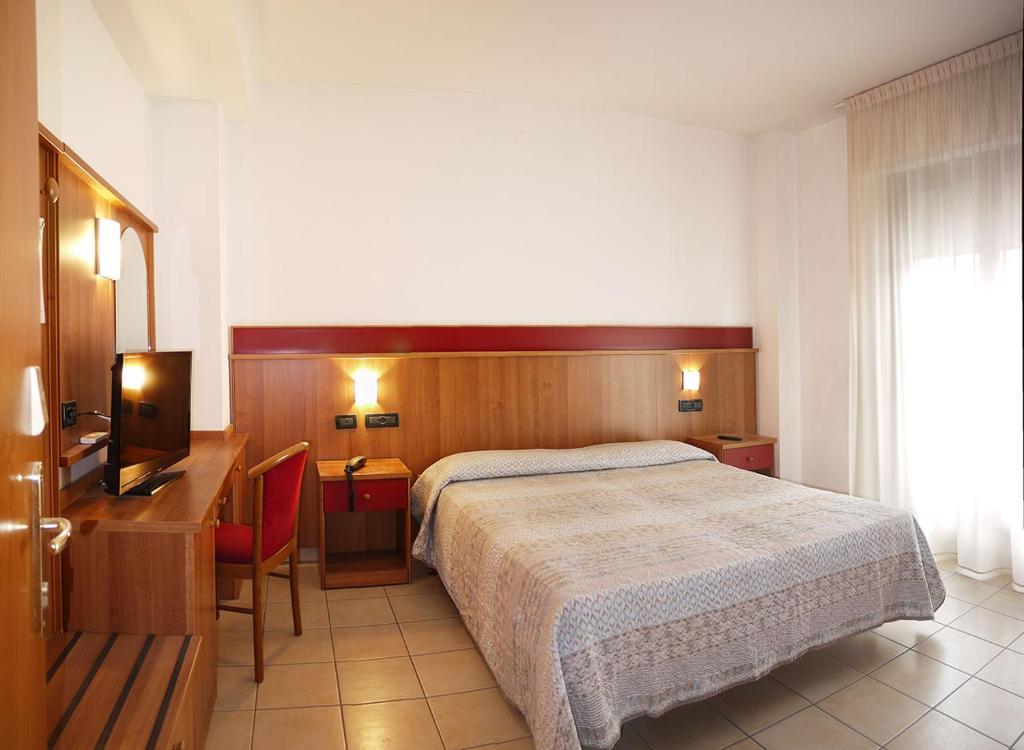 a bedroom with a bed and a desk and a television at Hotel Alla Rotonda in Lido di Jesolo