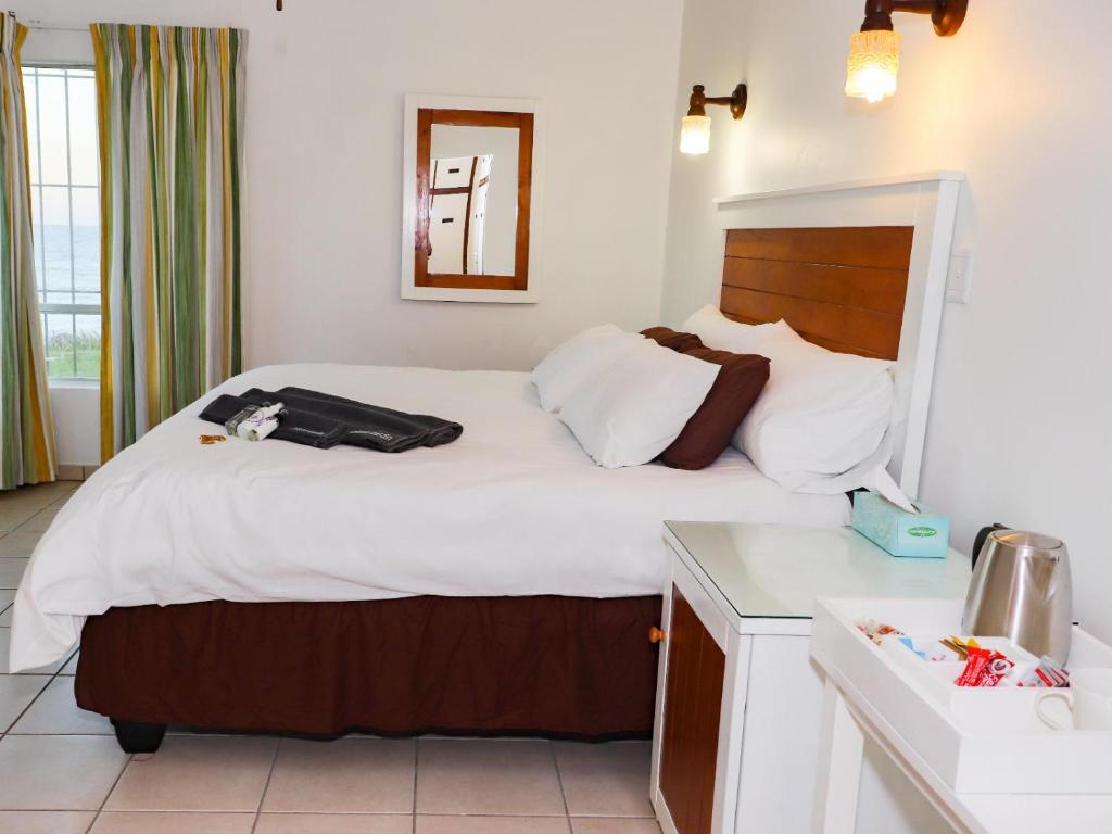 um quarto com uma cama grande e lençóis brancos em Black Rock Lodge em Port Edward