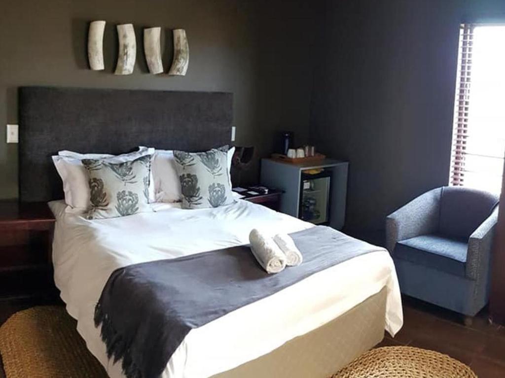 a bedroom with a large bed and a chair at Kusile Guest House in Burgersfort