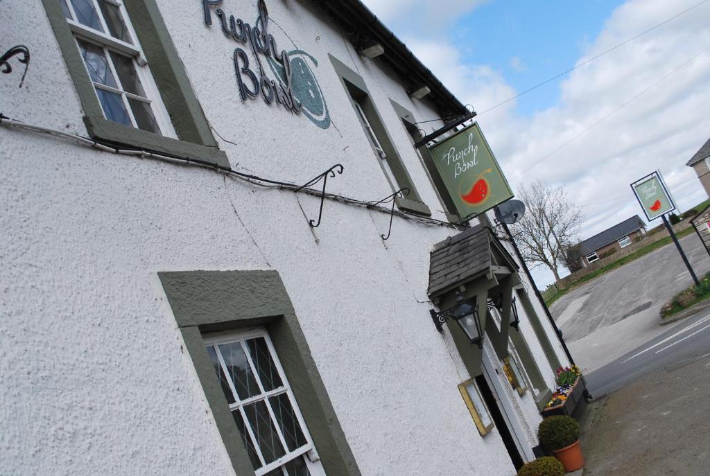 um edifício branco com um sinal na lateral em the punchbowl hotel em Kendal