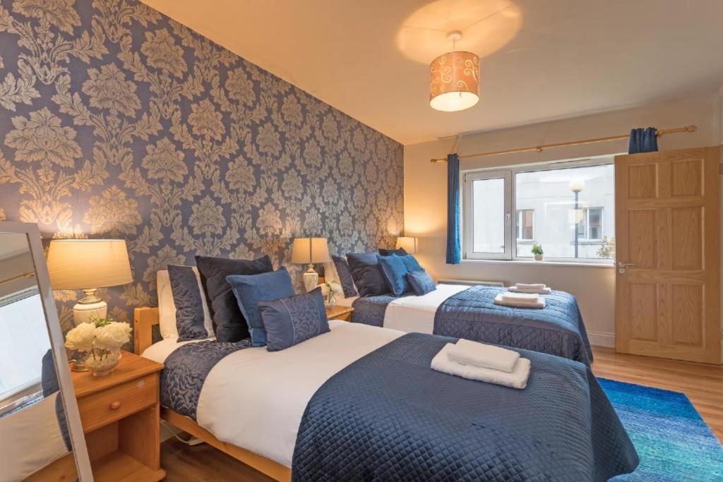 a bedroom with two beds with blue and white at Town Square Townhouse - Best Location in Galway in Galway
