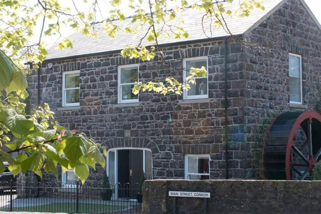 une maison en briques avec des fenêtres blanches et un panneau devant dans l'établissement Stone Flax Mill, à Connor