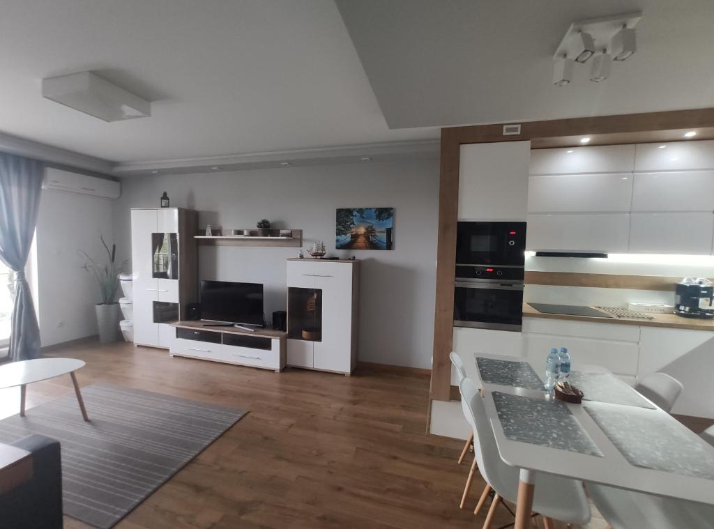 a kitchen and living room with white cabinets and a table at Apartament Żeglarski Wilkasy in Wilkasy