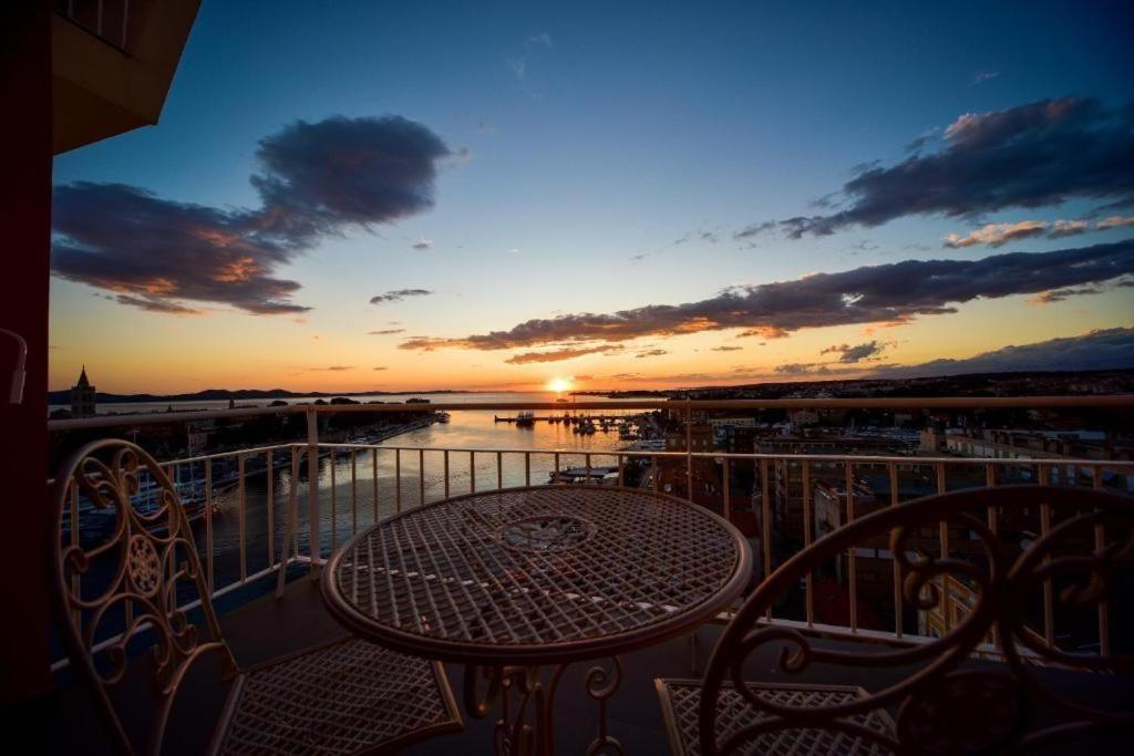 een tafel en stoelen op een balkon met een zonsondergang bij Aurora & Tramonto in Zadar