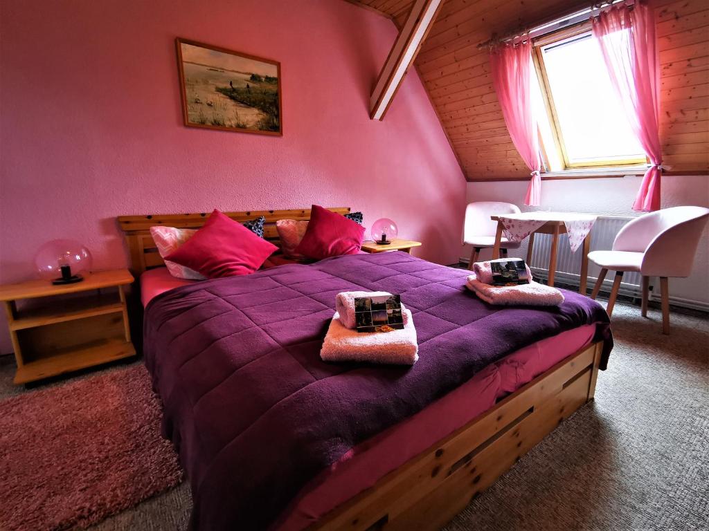 a bedroom with a purple bed with a table and chairs at Pension Jägerrast in Boek
