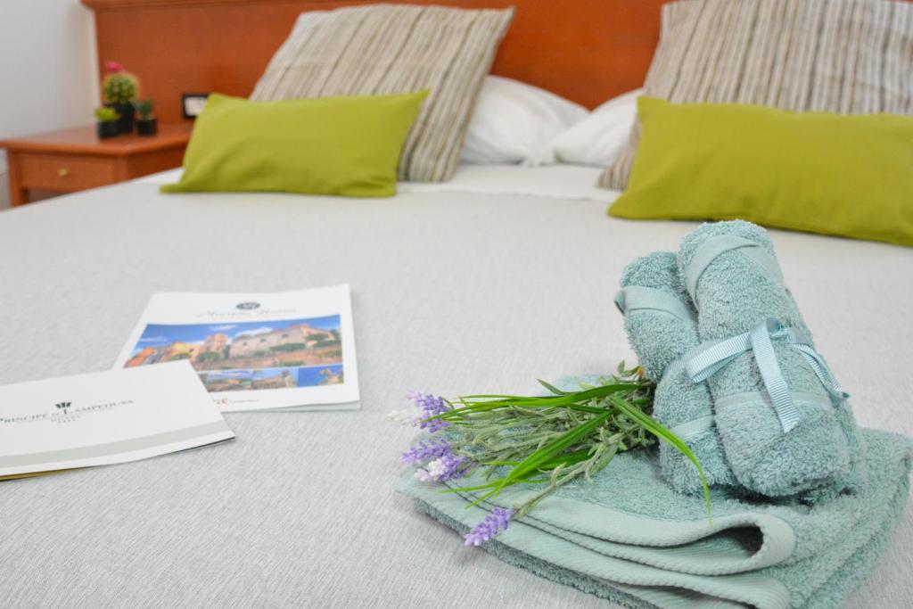 a towel on a bed with a book and flowers at Best Western Hotel Martello in Lampedusa