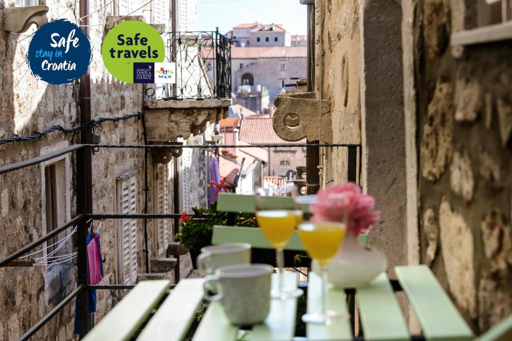uma mesa com bebidas e flores numa varanda em San Lorenzo Deluxe Room with Balcony em Dubrovnik