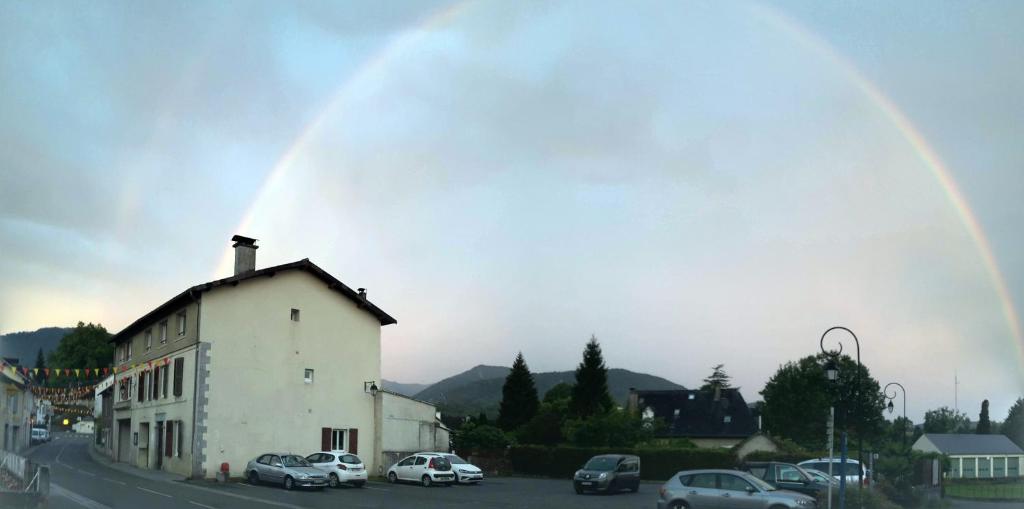 a rainbow over a building with cars parked in a parking lot at Le Loubens in Arette