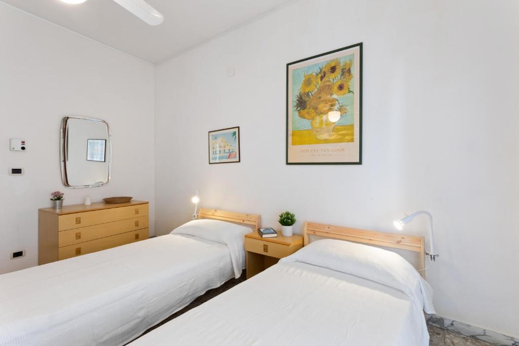 two beds in a room with white walls at Aci Castello Seaview Apartment with Parking in Aci Castello