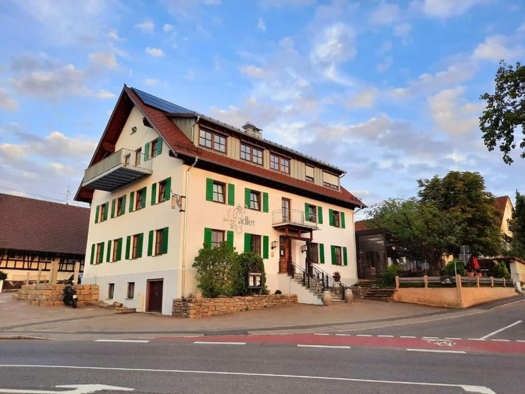 un bâtiment blanc avec volets verts dans une rue dans l'établissement Gasthof Adler, à Oberteuringen