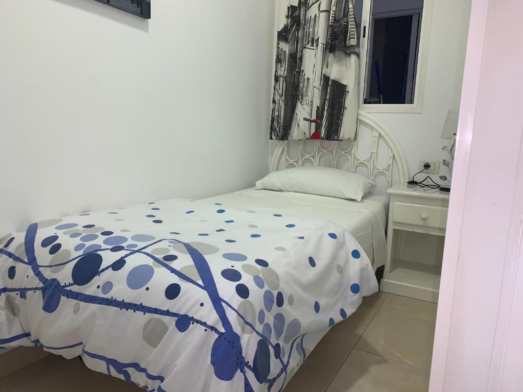 a bedroom with a bed with a blue and white comforter at Singol room IN APARTMENT SHARED in Los Cristianos PLAYA Las Vistas in Arona