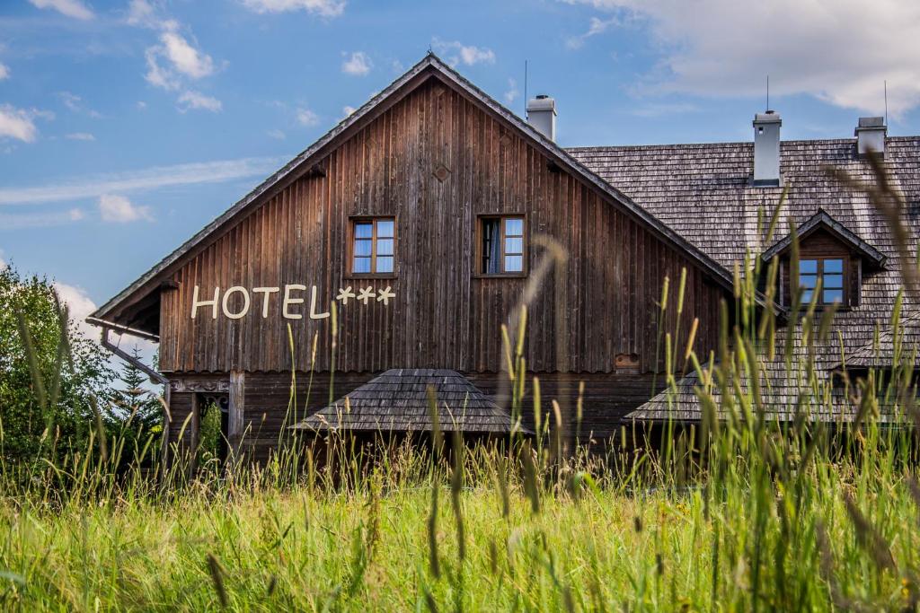 um antigo edifício de hotel de madeira num campo de relva alta em Karczma Regionalna Hotel GOŚCINNA CHATA em Wysowa-Zdrój